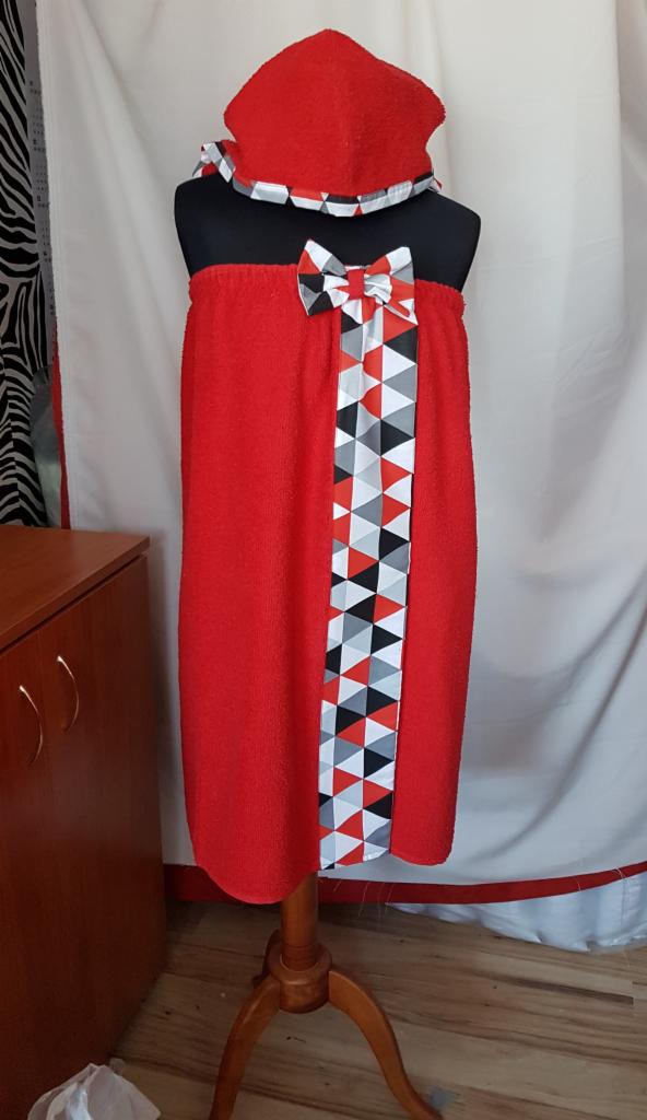 Czerwony ręcznik frotte z kapturem i ozdobną wstążką w geometryczne wzory, prezentowany na manekinie.