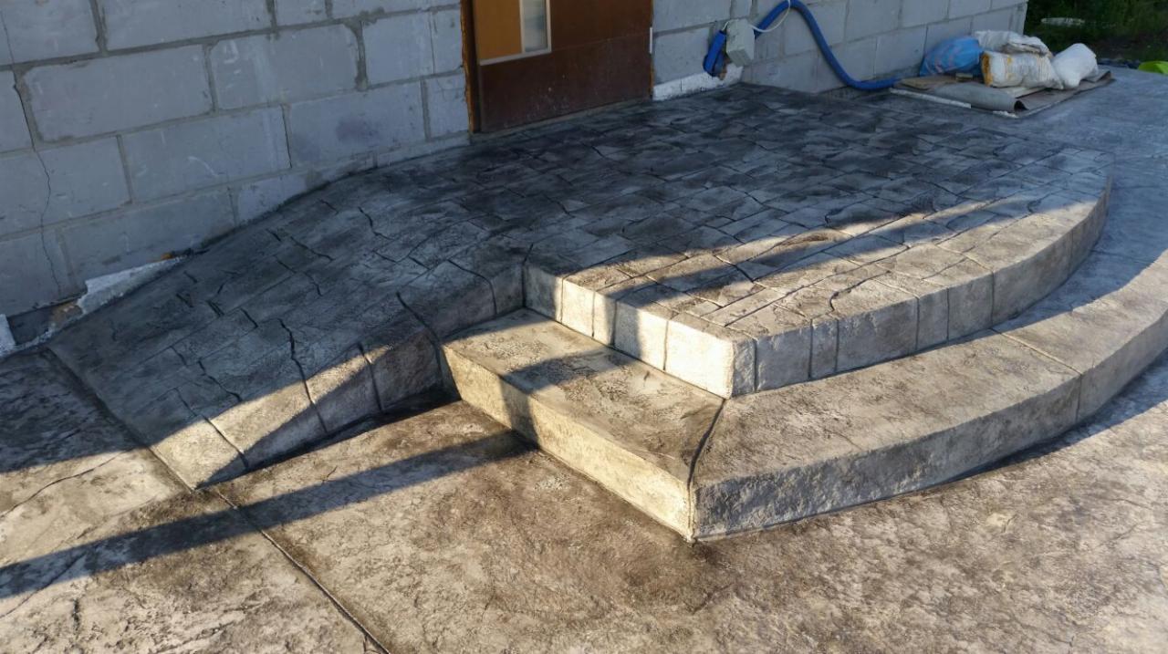 Schody wejściowe z betonu stemplowanego prowadzące do budynku z szarej cegły, z widocznymi śladami po procesie stemplowania betonu.