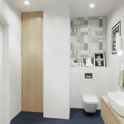 Nowoczesna łazienka z toaletą, umywalką nablatową na drewnianej szafce, wysoką szafą z jasnego drewna, ciemną podłogą w drobny wzór, białymi płytkami i fragmentem ściany w patchworkowy wzór.