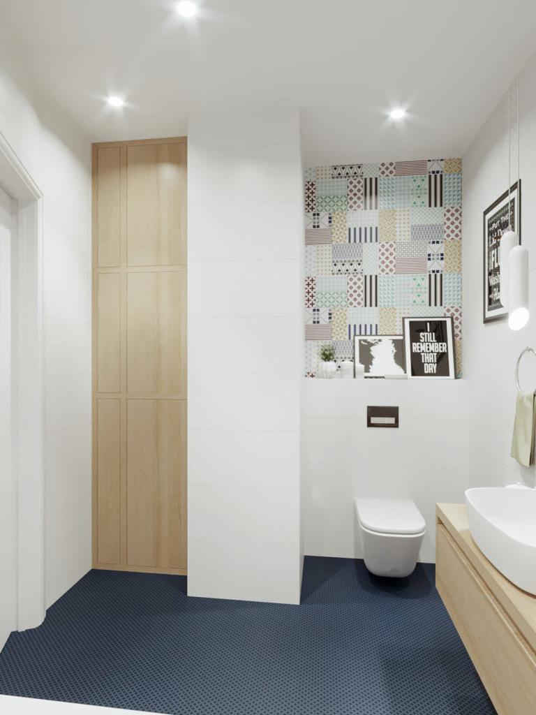 Nowoczesna łazienka z toaletą, umywalką nablatową na drewnianej szafce, wysoką szafą z jasnego drewna, ciemną podłogą w drobny wzór, białymi płytkami i fragmentem ściany w patchworkowy wzór.