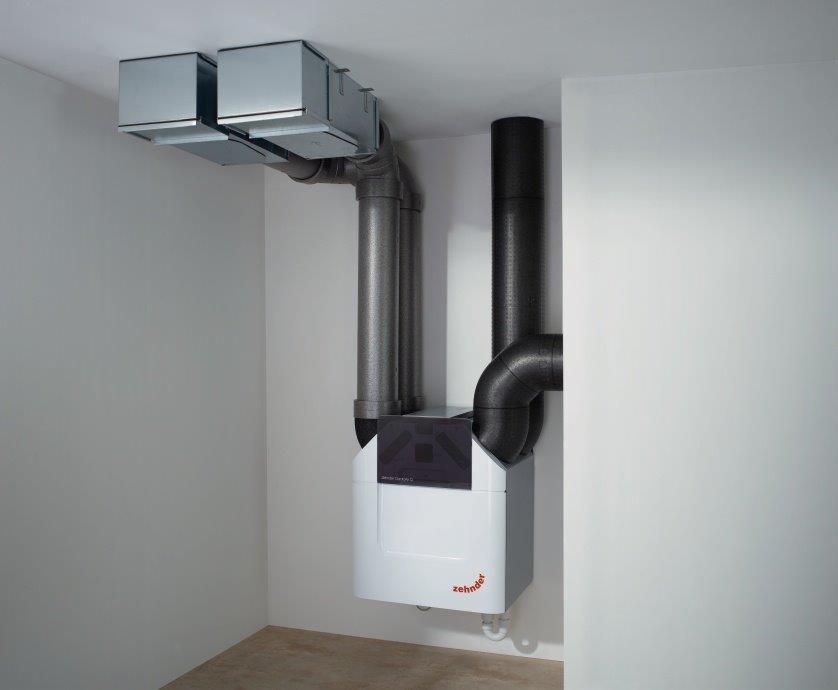 Centrala wentylacyjna Zehnder ComfoAir Q z szarymi przewodami wentylacyjnymi i czarną rurą izolacyjną w rogu pomieszczenia z białymi ścianami.