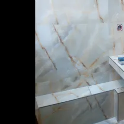 Jasne, marmurkowe płytki ułożone na ścianie i obudowie w łazience, widoczne narzędzia na blacie, gniazdko elektryczne w ścianie.