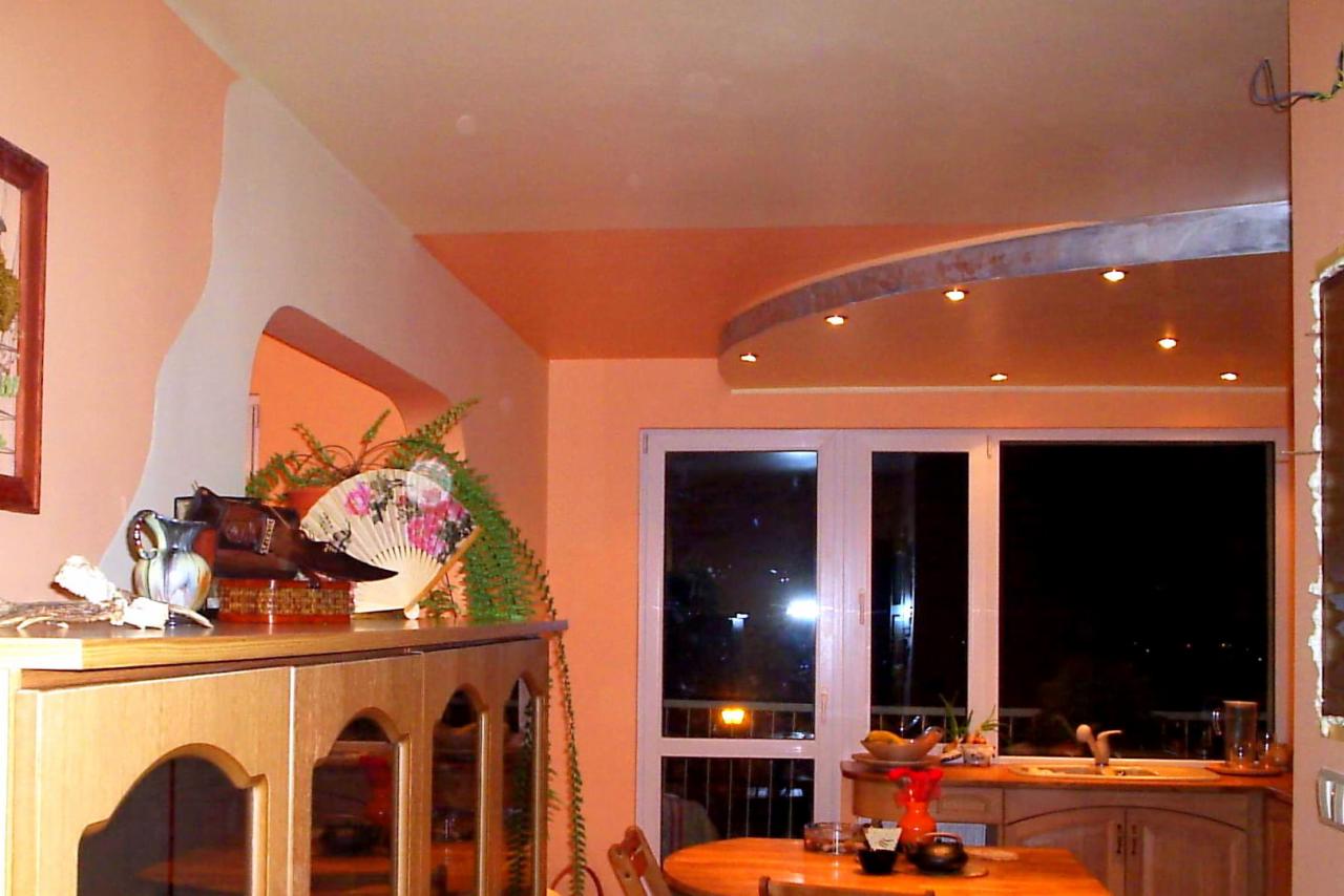 Wnętrze kuchni z elementami dekoracyjnymi, oświetleniem punktowym na suficie i widokiem nocnym za oknem balkonowym.