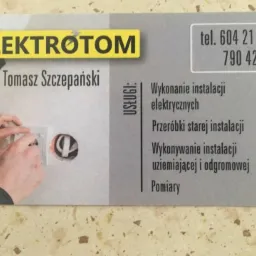 Zdjęcie wizytówki firmy Elektrotom Tomasz Szczepański, prezentującej montaż gniazdka elektrycznego w ścianie, z wykazem usług: wykonanie instalacji, przeróbki, uziemiające, odgromowe oraz pomiary.