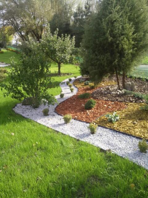 Kaskadowy ogród z białym żwirem, korą i drzewami, świeżo po pielęgnacji.