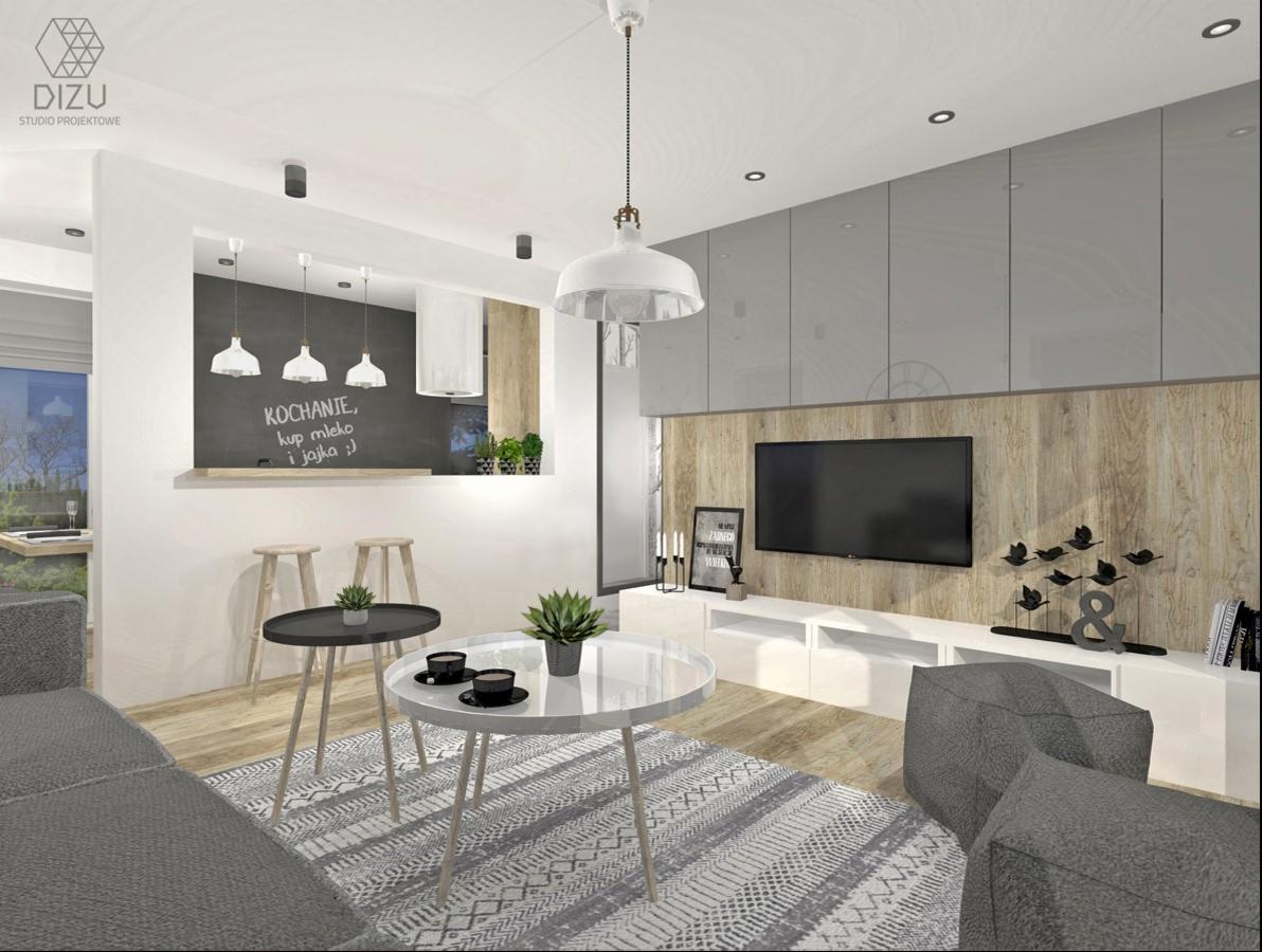 Wizualizacja salonu z aneksem kuchennym, ściana z tablicą kredową z napisem 'Kochanie, kup mleko i jajka :)', dwie okrągłe ławy, szara sofa i pufy, drewniana ściana z telewizorem i szafkami.