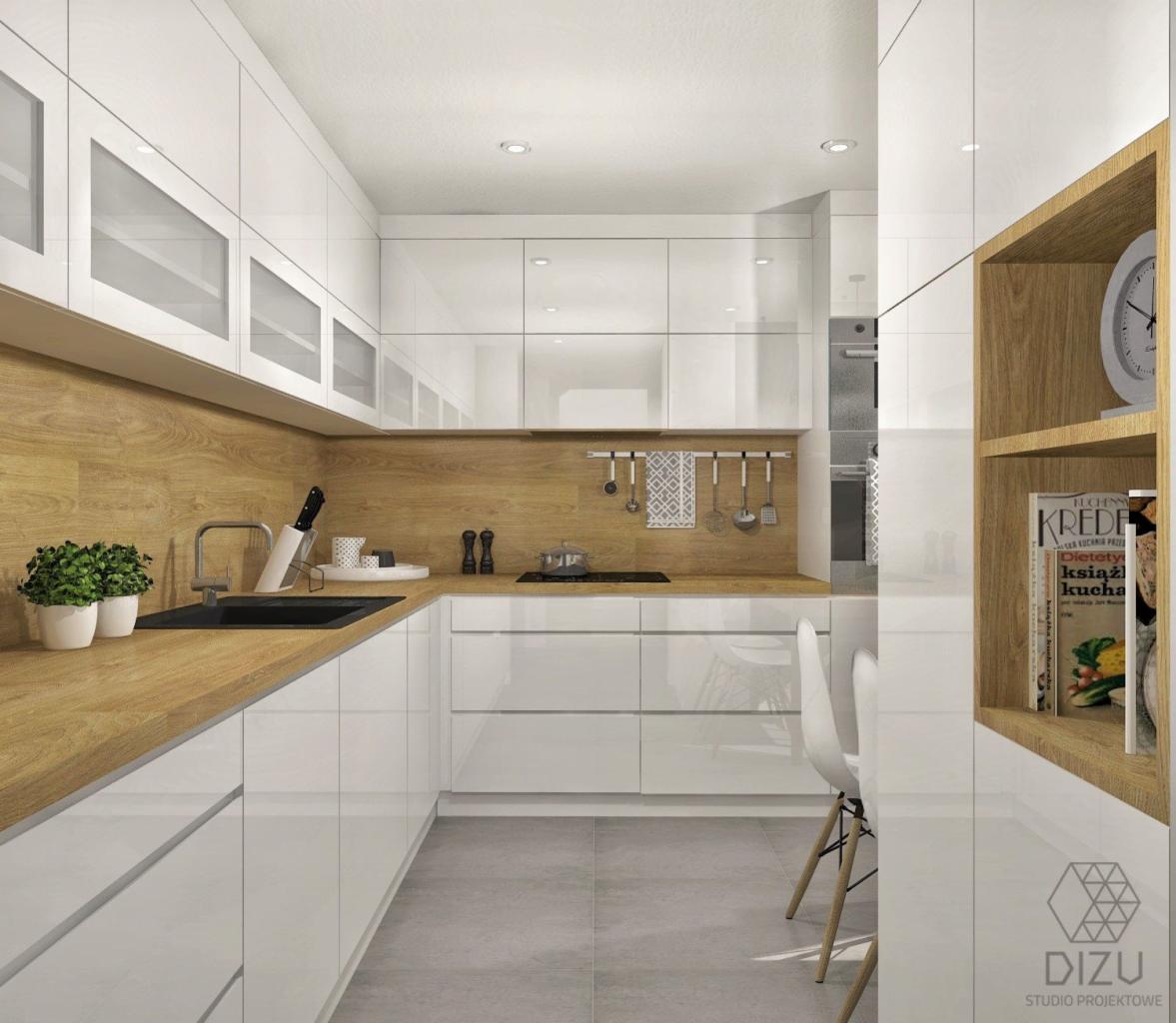 Nowoczesna kuchnia z białymi, lakierowanymi szafkami, drewnianym blatem i backsplashiem, czarnym zlewem i szarą podłogą; na blacie rośliny w doniczkach, a na półce książka kucharska i zegar.