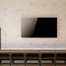 Salon w stylu industrialnym z białą ceglaną ścianą, telewizorem, drewnianą szafką RTV z metalowymi elementami, półkami z książkami i roślinami w doniczkach.