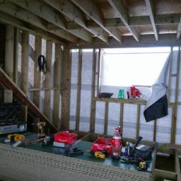 carpentry&joinery - Surowy stan budowy: drewniana konstrukcja ścian i stropu z widocznymi narzędziami i materiałami budowlanymi wewnątrz pomieszczenia.