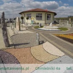 Ekspozycja zewnętrzna hurtowni kamienia z różnymi rodzajami nawierzchni, w tym ścieżki z kostki, rabaty z kolorowego żwiru i pionowe kamienne monolity.