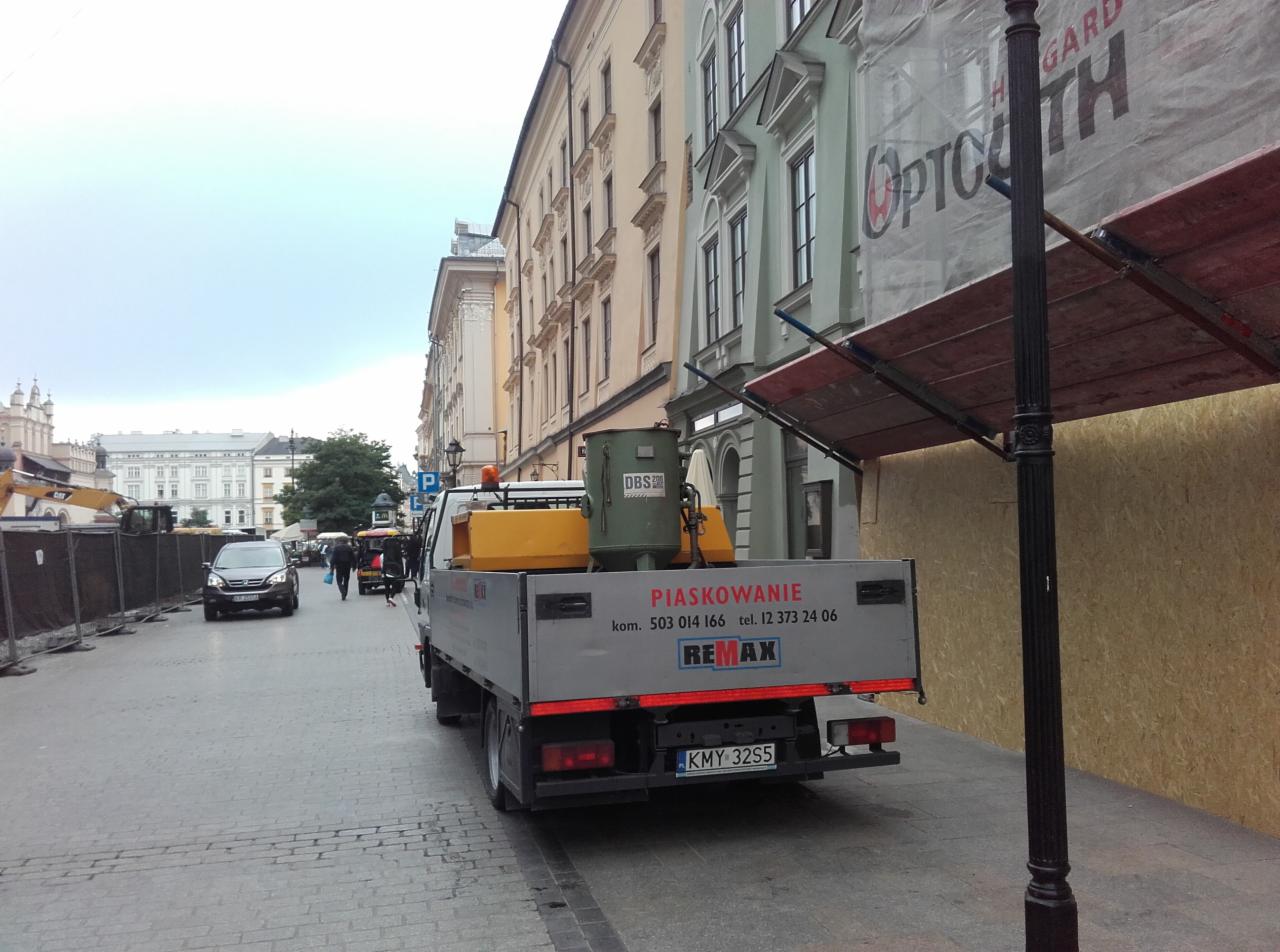 Ciężarówka z urządzeniem do obróbki strumieniowo-ściernej zaparkowana na ulicy w Krakowie, widoczny napis 'Piaskowanie' na burcie