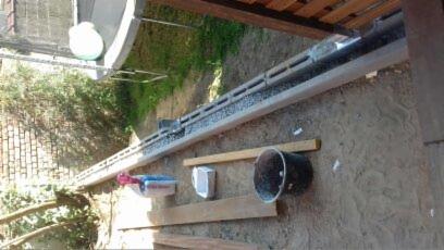 Montaż parapetu zewnętrznego z pustaków wentylacyjnych, widoczne narzędzia i wiadro na ziemi.