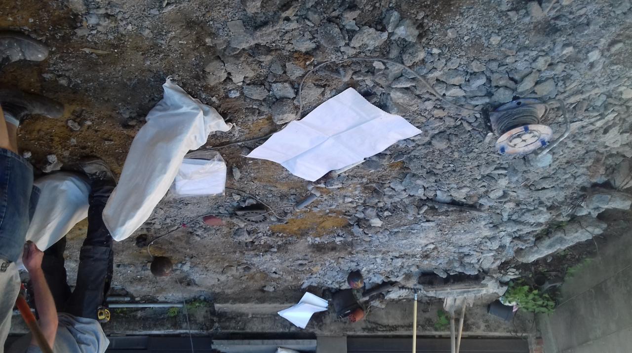 Przygotowanie podłoża pod wylewkę: gruz, piasek, folia ochronna i narzędzia na placu budowy.