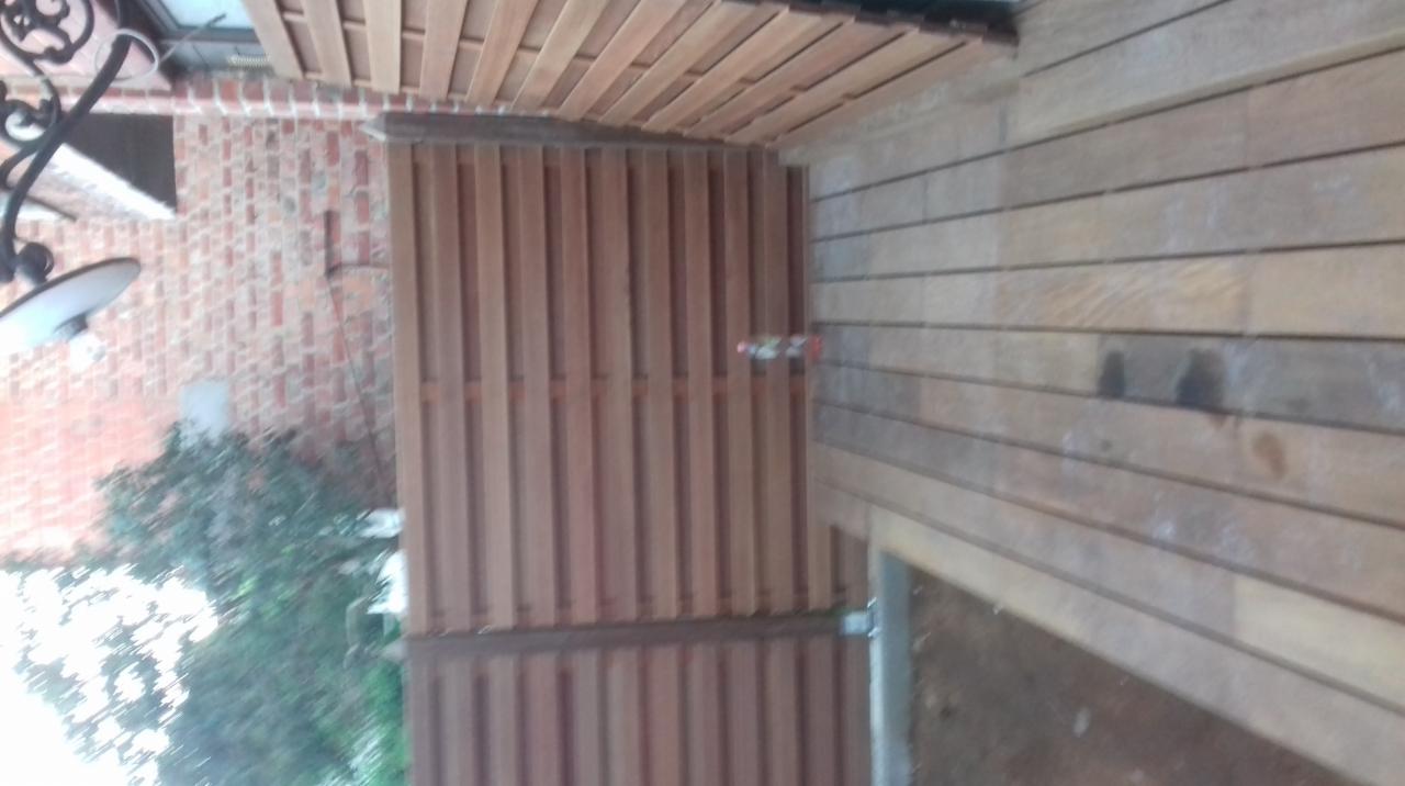 Drewniana elewacja budynku z elementami ceglanymi i lampą zewnętrzną, widok z dołu.