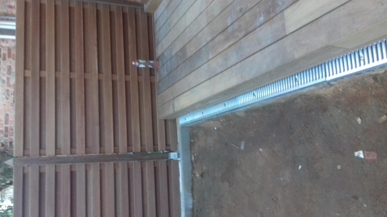 Drewniany taras z odpływem liniowym i ogrodzeniem z pionowych desek, widok z góry.