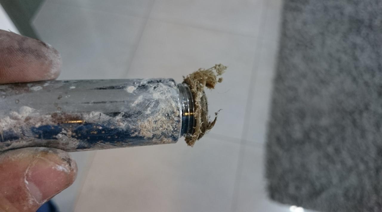 Zanieczyszczona rura w ręce, widoczne pozostałości po pracach wykończeniowych. Rura pokryta pyłem i zabrudzeniami, co sugeruje niedokładne sprzątanie po remoncie.