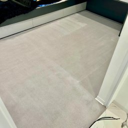 Usługi Sebastian Walczak - Jasnoszary dywan po czyszczeniu, widoczny w pokoju dziecięcym z białymi meblami i czarnymi akcentami, minimalne ślady użytkowania.