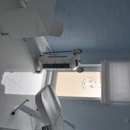 Yasumi Instytut Zdrowia i Urody - Jasne wnętrze gabinetu kosmetycznego z fotelem zabiegowym, lampą i oknem z naklejką logo.