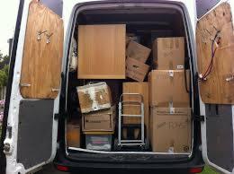 Wnętrze furgonetki załadowanej kartonami i meblami podczas przeprowadzki w Walsall. Widoczne otwarte tylne drzwi i wózek transportowy.