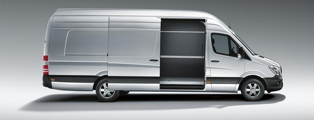 Srebrny furgon z otwartymi drzwiami przesuwnymi, widok z boku, pusta przestrzeń ładunkowa z zabezpieczeniami na ścianach.