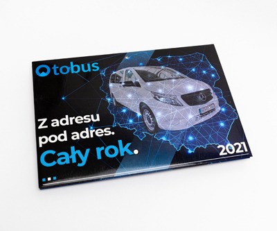 Błyszczący, czarny katalog firmowy z grafiką białego vana na tle mapy Polski połączonej niebieskimi liniami, hasłem reklamowym i rokiem 2021.