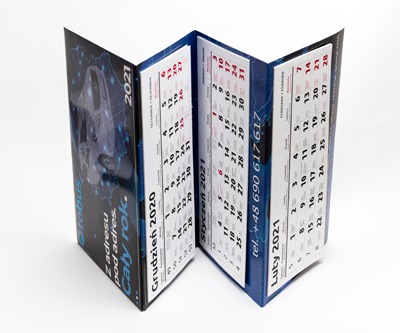 Rozłożony, trójdzielny kalendarz książkowy z grafiką pojazdu i danymi kontaktowymi firmy, prezentujący miesiące grudzień 2020, styczeń i luty 2021 na białym tle.