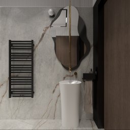 Inspiration Studio - Nowoczesna łazienka z umywalką wolnostojącą, grzejnikiem drabinkowym i asymetrycznym lustrem na tle marmurowej ściany. Minimalistyczny design z akcentami złota.