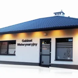 Budynek gabinetu z napisem Gabinet Weterynaryjny, okna ozdobione naklejkami z sylwetkami zwierząt, ciemny dach i jasna elewacja.