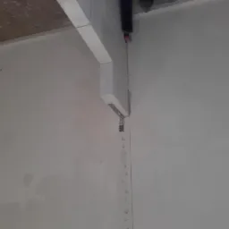 Ściana po nałożeniu gładzi, widoczny profil pod sufitem i ślady po szpachlowaniu na łączeniu płyt gipsowo-kartonowych.