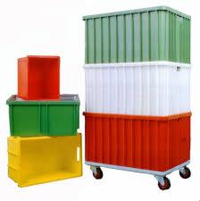 Stos kolorowych, plastikowych pojemników przemysłowych: czerwony na zielonym, żółty obok, oraz wieża z pomarańczowego, białego i zielonego pojemnika na kółkach.