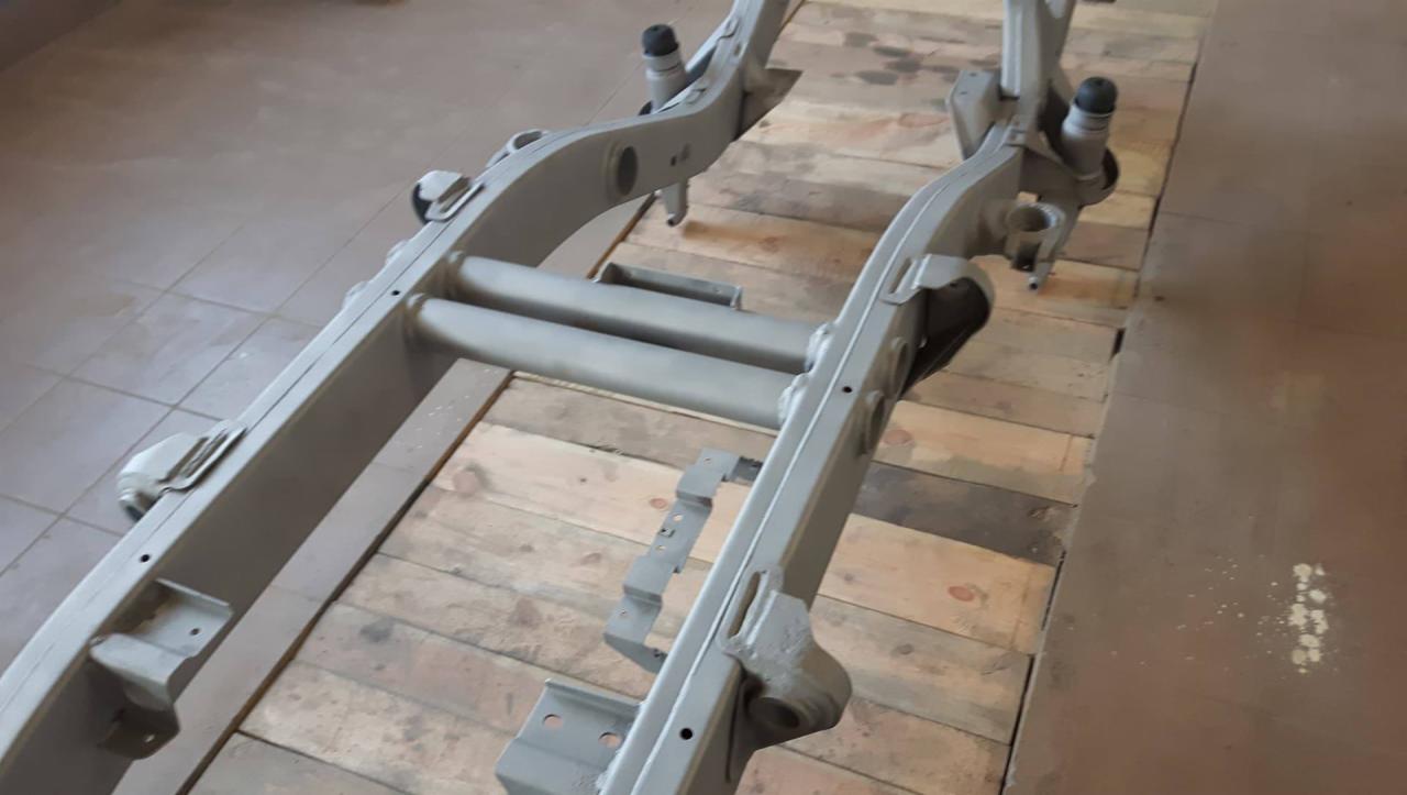 Metalowa rama pojazdu po piaskowaniu i malowaniu proszkowym, leżąca na drewnianych paletach, widoczne spawy i otwory montażowe.