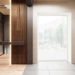 MADO DESIGN - Nowoczesne wnętrze z drewnianą ścianą z pionowymi listwami i oświetleniem LED, pionowa zielona ściana z roślinami, widok na zewnątrz przez duże okno, podłoga z płytek w dwóch odcieniach szarości.