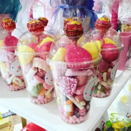 Słodkie upominki w plastikowych kubeczkach z lizakami, przygotowane w firmie z Rawa Mazowiecka. Kolorowe cukierki i pianki tworzą apetyczną kompozycję.