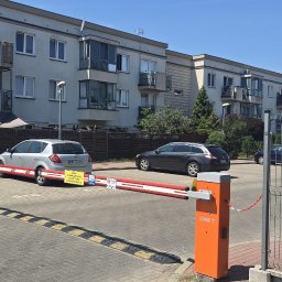 Grupa Oktagon Sp. z o.o. - Automatyczny szlaban CAME i budka ochrony z kamerą monitoringu przy wjeździe na osiedle mieszkaniowe, z tablicą 'Obiekt Chroniony Grupa Oktagon'.