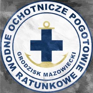 Okrągłe logo Ochotniczego Pogotowia Ratunkowego Grodzisk Mazowiecki z granatowym krzyżem i kotwicą na białym tle, otoczone granatowym obramowaniem z napisem.