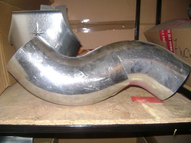 Elementy metalowe rynny, jeden z gwiazdą, leżące na półce w magazynie.