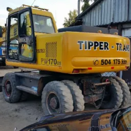 Żółta koparka kołowa PW170ES firmy Tipper-Trans z Wyszkowa, widoczna z tyłu, zaparkowana na terenie budowy, z numerem telefonu na karoserii.