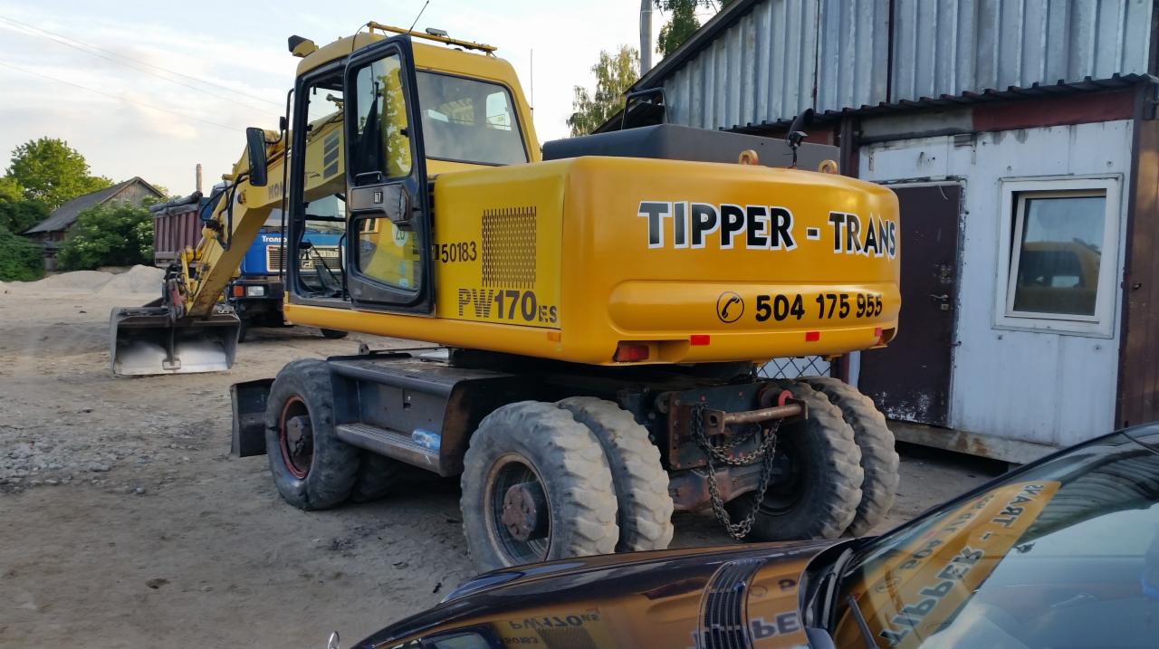Żółta koparka kołowa PW170ES firmy Tipper-Trans z Wyszkowa, widoczna z tyłu, zaparkowana na terenie budowy, z numerem telefonu na karoserii.