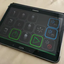 Tablet Samsung wyświetlający interfejs inteligentnego domu z przyciskami do sterowania oświetleniem i innymi funkcjami, widoczne ikony włączania/wyłączania, regulacji jasności oraz procentowe...