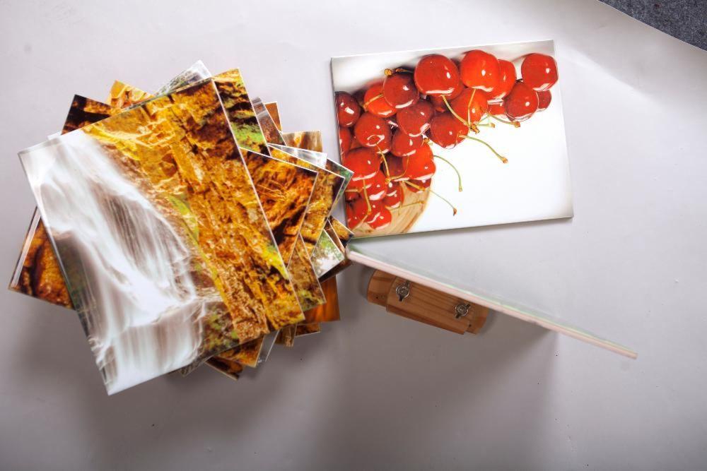 Stos płytek z nadrukiem wodospadu ułożonych kaskadowo obok płytki z motywem wiśni, wsparte na drewnianym elemencie montażowym.