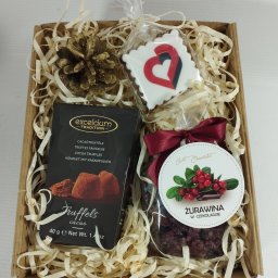 Endi-Mar Sp. z o.o. - Elegancki kosz prezentowy z truflami, żurawiną w czekoladzie i piernikiem w kształcie serca, wypełniony dekoracyjnym siankiem w kartonowym pudełku.