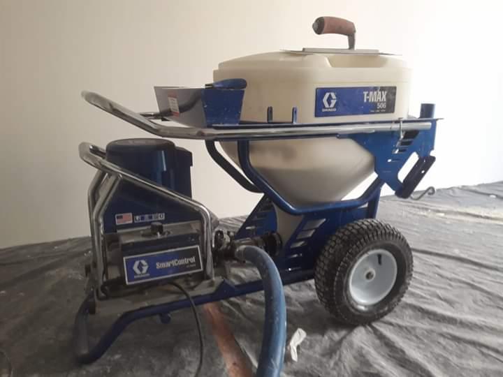 Agregat malarski Graco T-Max 506 na folii ochronnej, gotowy do pracy. Widoczne detale: zbiornik na farbę, panel sterowania SmartControl i koła. Urządzenie czeka na użycie.