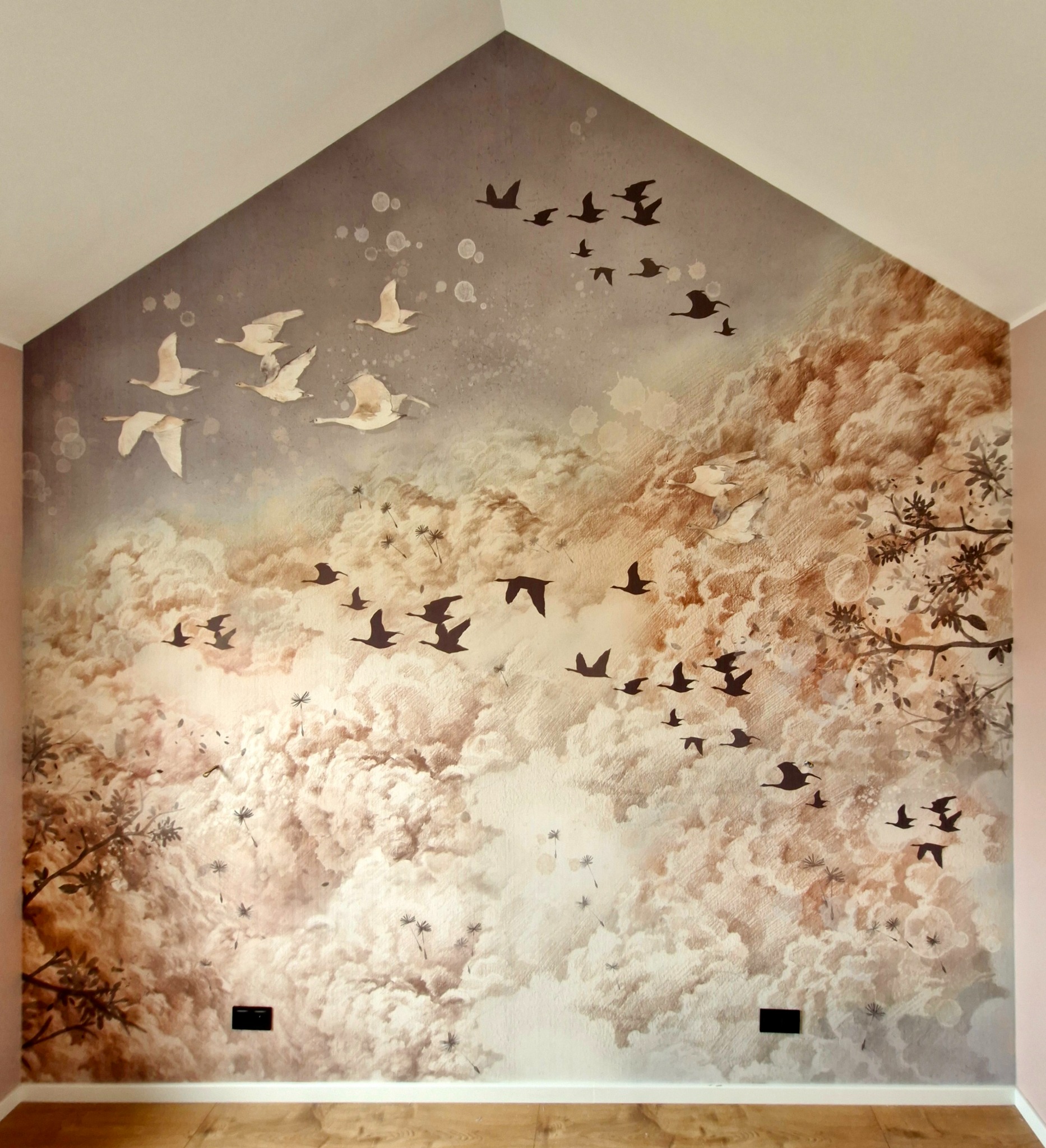 Ściana z fototapetą przedstawiającą niebo z ptakami, w pokoju z drewnianą podłogą. Fototapeta dopasowana do kształtu ściany ze skosem.
