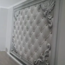 Ściana z dekoracyjnym panelem tapicerowanym w ramie z ornamentami i kryształkami, widok pod kątem.