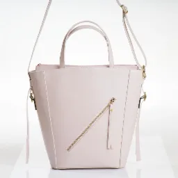 Jasnoróżowa torebka damska z krótkimi uchwytami i długim paskiem, z ukośnym złotym zamkiem błyskawicznym na przedniej ściance, na białym tle.