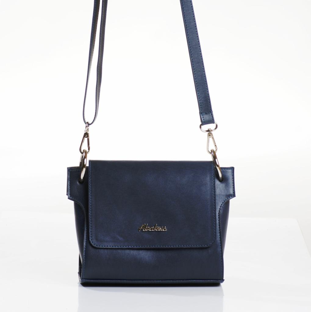 Elegancka, granatowa torebka damska na ramię z metalowymi detalami i subtelnym, złotym logo na klapie, prezentowana na jasnym, minimalistycznym tle.