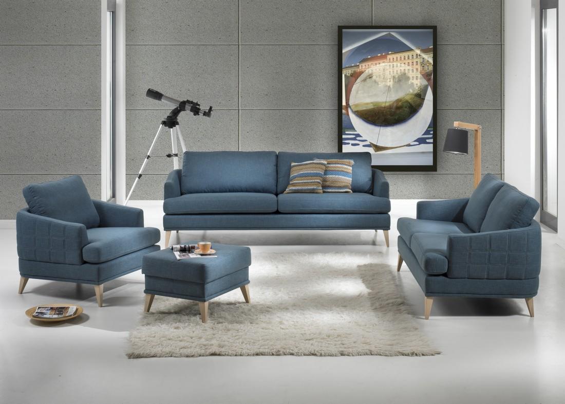 Niebieski zestaw wypoczynkowy: sofa dwuosobowa, fotel i pufa na tle szarej ściany z teleskopem i abstrakcyjnym obrazem.