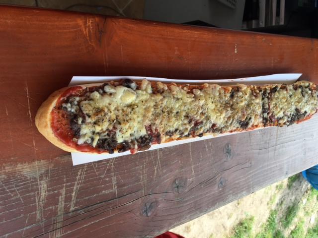 Długa zapiekanka z mięsem i serem, podawana na papierowej tacce, przygotowana w Gniewinie.