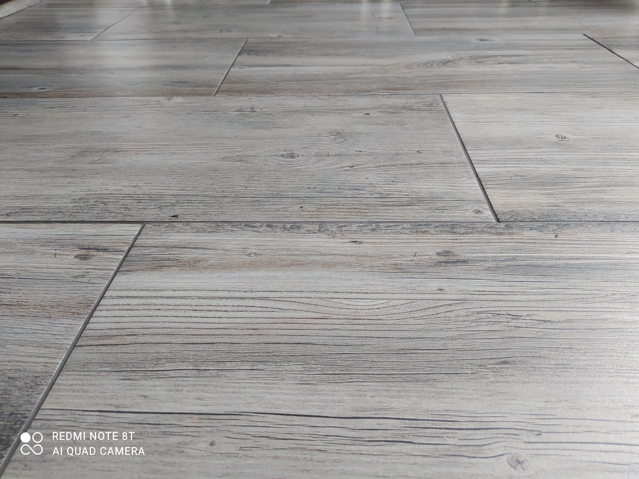 Ułożony parkiet z jasnych, drewnopodobnych paneli, widok z niskiej perspektywy podkreślający teksturę i układ.