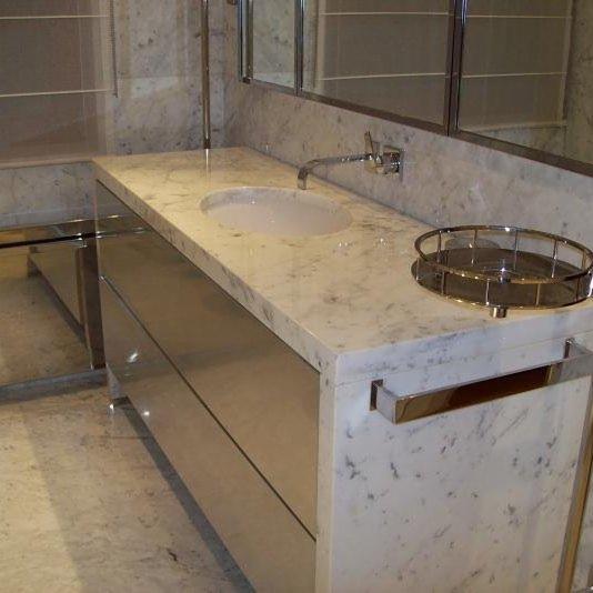 Łazienka z marmurowym blatem, wbudowaną umywalką i chromowanymi detalami, widoczne odbicie w lustrze.